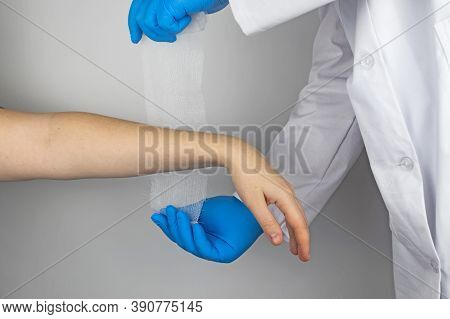 The Traumatologist Puts A Bandage On The Forearm Of The Female Patient. The Concept Of Help With Fra