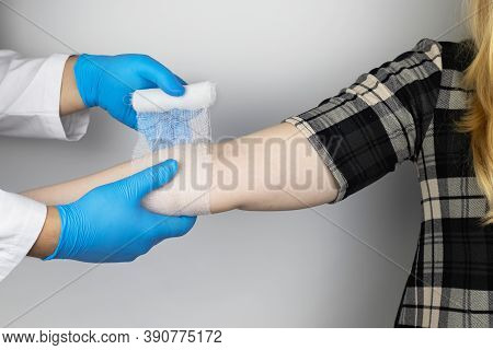 The Traumatologist Puts A Bandage On The Elbow Of The Female Patient. The Concept Of Help With Fract
