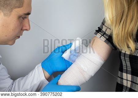 The Traumatologist Puts A Bandage On The Elbow Of The Female Patient. The Concept Of Help With Fract