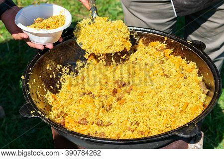 Big Cauldron With Tasty Pilaw Just Cooked Outdoors On Picnic On Sunny Day