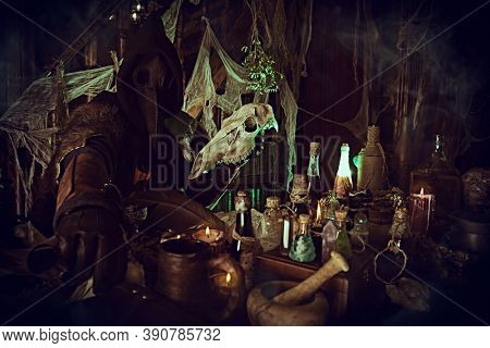 The plague doctor is working at his desk, inventing a cure for bubonic plague. The atmosphere of mysticism. Historical reenactment. Halloween. 