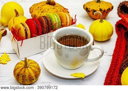 French Macarons In Autumn Colors With Cup Of Hot Tea
