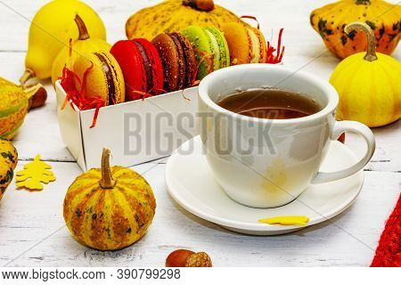 French Macarons In Autumn Colors With Cup Of Hot Tea