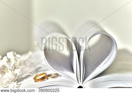 Blurred Background Of Wedding Rings And Open Book An Open Book With A Heart Folded From Folded Sheet