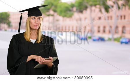 Confuso Graduate Woman Holding tavoletta digitale contro un apprendistato come sfondo la costruzione