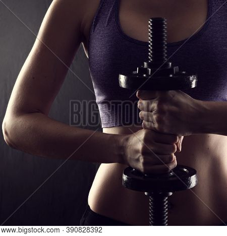 Slim Athletic Woman Holding Dumbbell In The Hand On Black