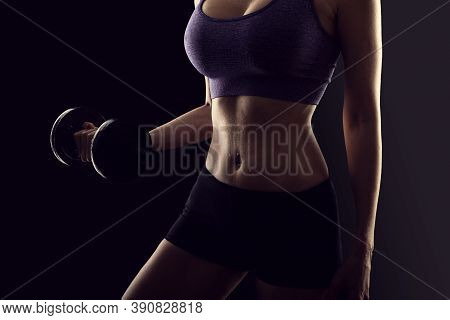 Slim Athletic Woman Holding Dumbbell In The Hand On Black