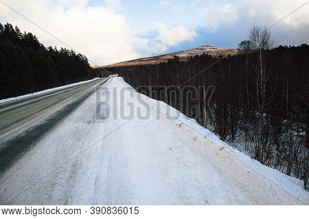 Tire Tracks In The Snow, Winter Road, Empty Road In Winter Goes Far To The Horizon, Covered With Sno