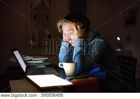 Shocked Teenger Studying Night At Home With Laptop And Tablet Pc. Online Learning, Distance Lessons,