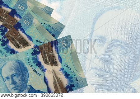 5 Canadian Dollars Bills Lies In Stack On Background Of Big Semi-transparent Banknote. Abstract Busi
