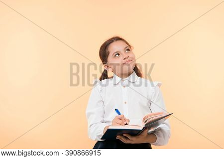 Child School Uniform Kid Doing Homework. Child Girl School Uniform Clothes Hold Book And Pen. Girl C