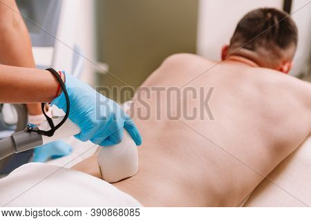 Unrecognizable Man Getting Laser Hair Removal On His Lower Back, Copy Space. Beautician Removing Low