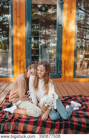 Happy Kids Sitting On The Terrace Of Their House In Autumn