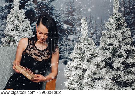 Beautiful Woman With Christmas Present At Fir Trees.