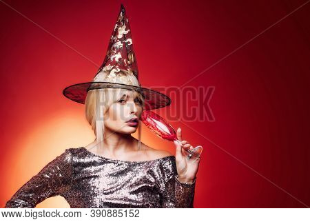 Gelightful Blonde Lady With A Glass Of Champagne On Red Background. Beautiful Surprised Woman In Wit