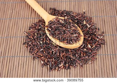 arroz preto com colher de pau, na esteira de bambu