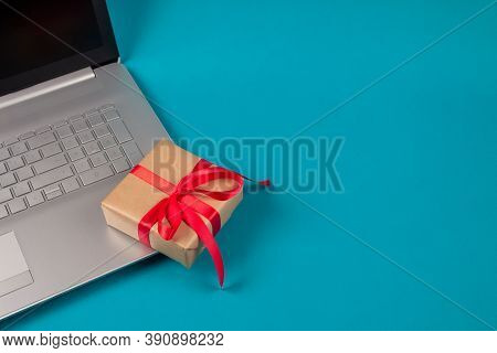 Front View On Laptop Computer And Present Box With Red Bow On Green Background With Copyspace For Yo
