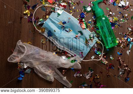 Facemask and sanitizer bottle droped on flor with confetti after celebration new year 2021 party background stock image