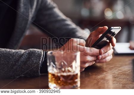 Close Up View Of Man In Formal Wear That Sits In The Cafe With Phone In Hands And Drink Of Alcohol O
