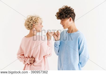 Image of happy woman standing near her brother isolated over white background and made up by pinky while showing diddle gesture under back
