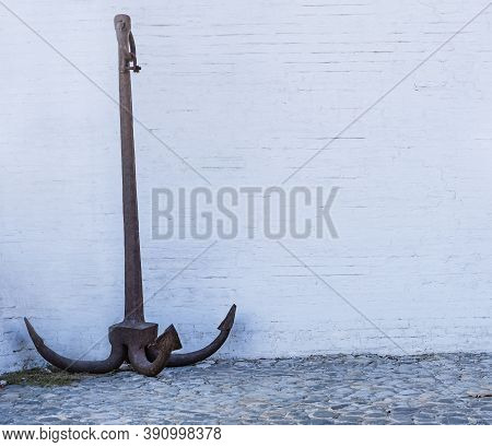 Large Iron Anchor On White Brick Wall Background