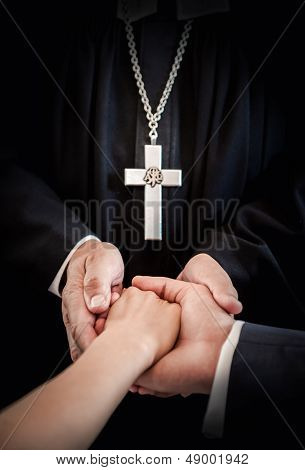 Priest Holding Bride's And Groom's Hands During Wedding Ceremony