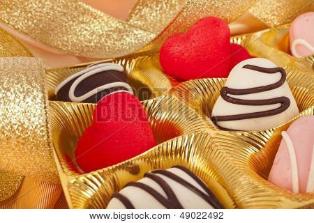 cuori di cioccolato e marchpane caramelle su sfondo dorato stoffa di seta con texture 