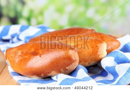 Empanadillas al horno frescos, en mesa de madera, sobre fondo brillante