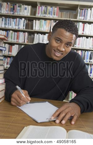 Portret van een Afrikaanse Amerikaanse mannelijke student maken van aantekeningen in het college library