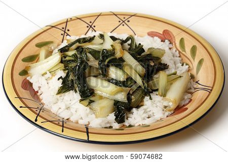 A plate with bok choi asian cabbage chopped and sauteed with sesame oil and soy sauce, served on a bed of white jasmine rice