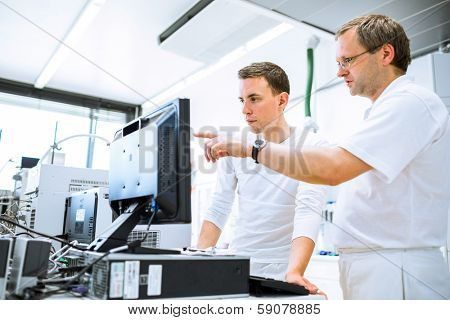 Team of researchers carrying out experiments in a lab (shallow DOF; color toned image)