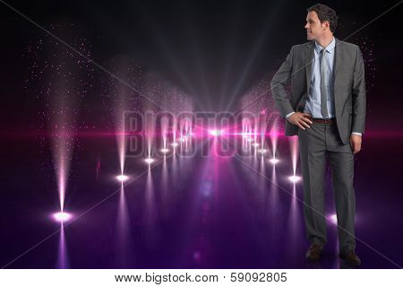 Smiling businessman with hand on hip against cool nightlife lights