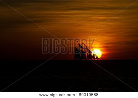 Sailboat silhouette crossing setting sun