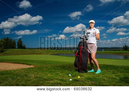 Young cheerful woman with bag and bottle of water on a golf field