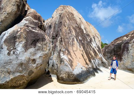Little boy at tropical beach among huge granite boulders at Virgin Gorda, BVI, Caribbean