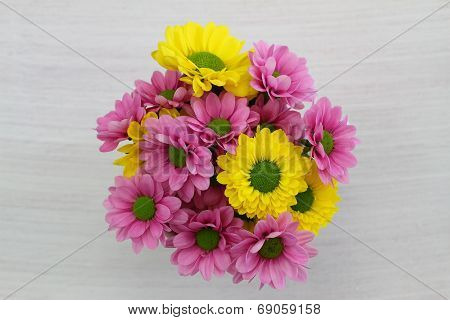 Yellow and pink Santini flower bouquet on white wood