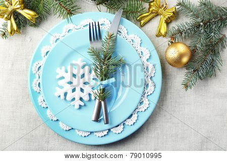 Christmas table setting in blue, golden and whitec olors on grey tablecloth background