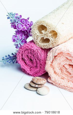 Spa towels rolls flower and stones lying on shite background. Space for your text. Vertical composition.