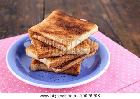 Toast bread on blue plate with pink napkin, on wooden table background