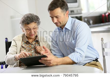 Man with elderly woman using digital tablet
