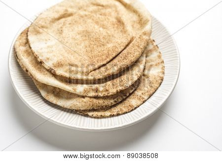 Brown pita bread in a plate on white background.