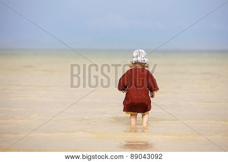 Child Walking On Fine Sand Through The Water