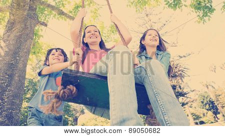 Low angle view of kids pushing mother on swing in playground