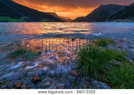 Beautiful view of the lake Resia. Dramatic sky and colorful sunset. Alps, Italy, Europe.