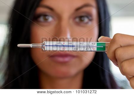 a woman holding a clinical thermometer hindquarters. symbolic photo for sick and fever