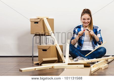 Woman Moving Into Apartment Assembly Furniture.