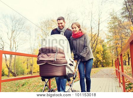 love, parenthood, family, season and people concept - smiling couple with baby pram in autumn park