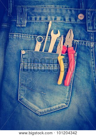 Several tools on a denim workers pocket.
