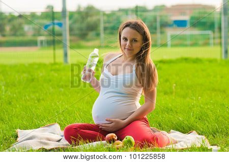 young pregnant woman holding bottle of water