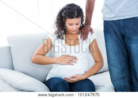 Man comforting pregnant woman sitting on sofa at home